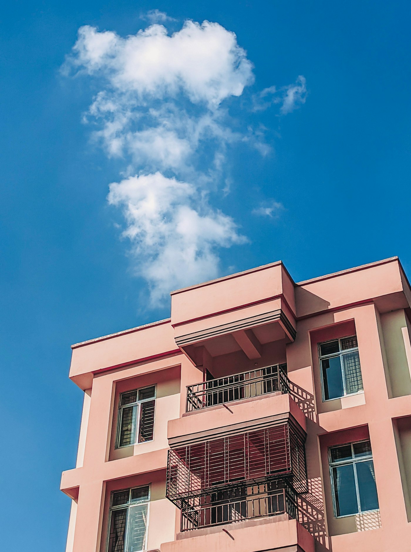 Pink and white residential apartment building against a blue sky